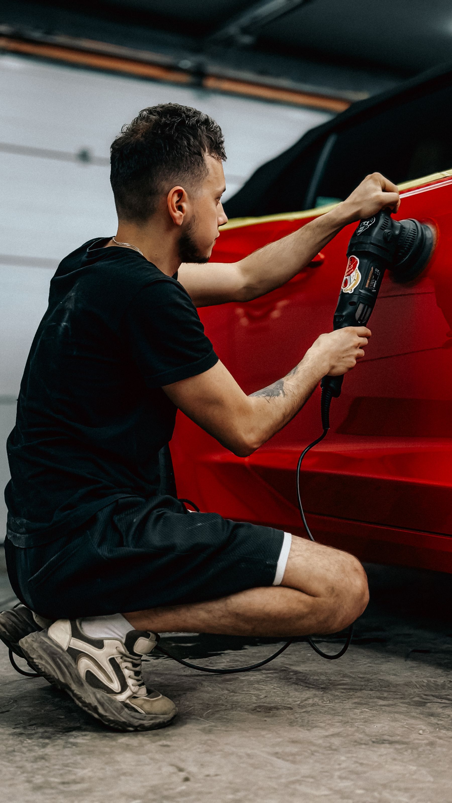 Rotary polisher moving across red vehicle paint